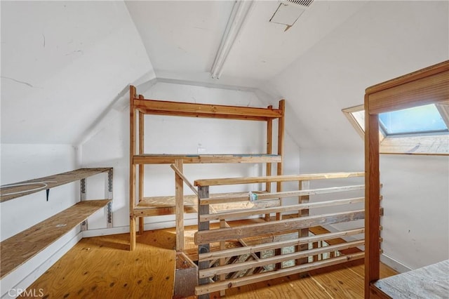 bonus room featuring vaulted ceiling with skylight and hardwood / wood-style flooring