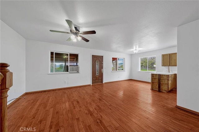 unfurnished living room with hardwood / wood-style flooring, cooling unit, baseboards, and a ceiling fan