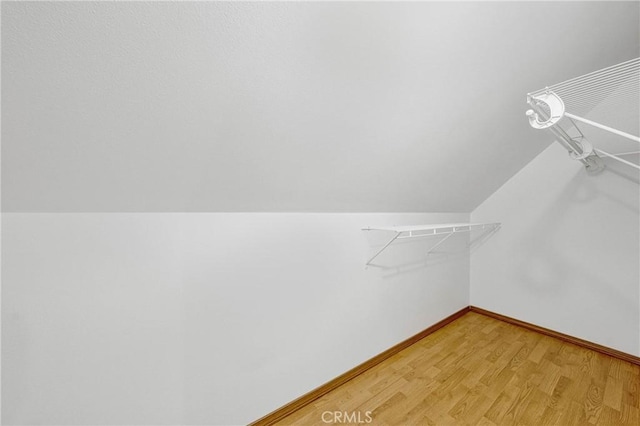 walk in closet featuring light wood-type flooring and lofted ceiling