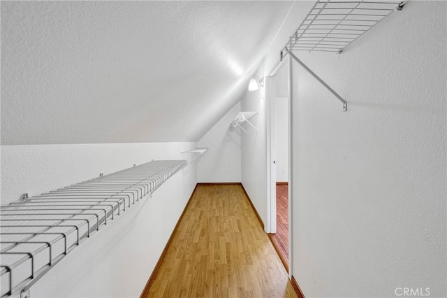 walk in closet featuring light wood-style floors and vaulted ceiling