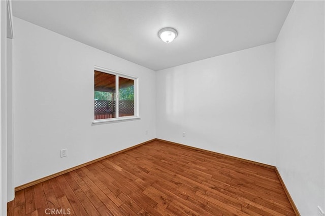 empty room with hardwood / wood-style flooring and baseboards