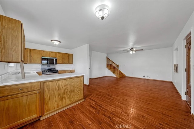 kitchen with open floor plan, stainless steel appliances, dark wood-type flooring, and light countertops