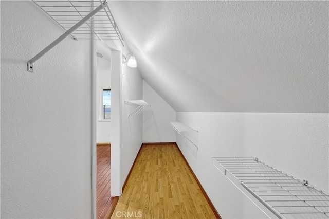 walk in closet featuring light wood-type flooring and lofted ceiling