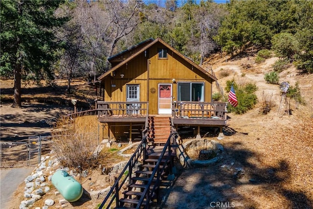 chalet / cabin featuring a wooded view, a wooden deck, and stairs