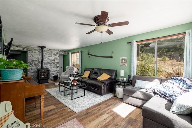 living room with a wood stove, ceiling fan, and wood finished floors