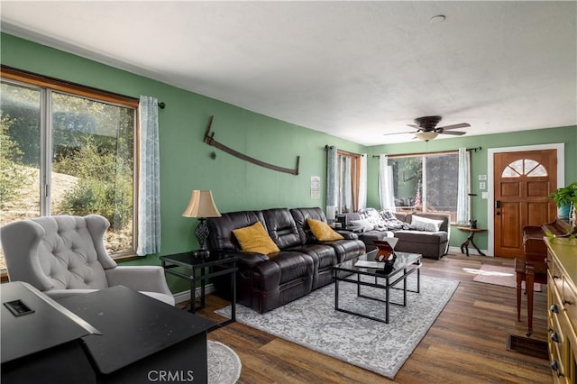 living room with ceiling fan, baseboards, and dark wood finished floors