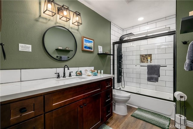 full bathroom featuring vanity, combined bath / shower with glass door, wood finished floors, and toilet