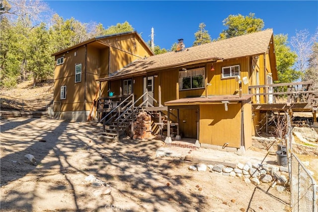 rear view of property featuring a shingled roof