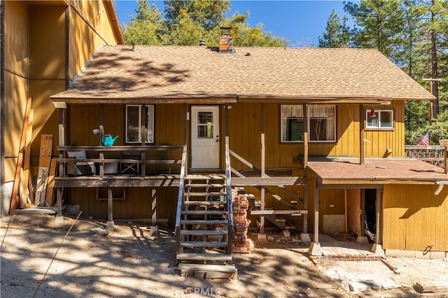 view of front of house with a chimney, stairway, and roof with shingles