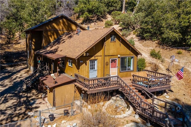 rustic home with a shingled roof, fence, a wooden deck, and stairs