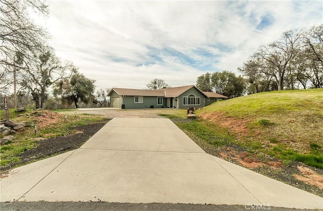 view of front facade featuring an attached garage, concrete driveway, and a front yard