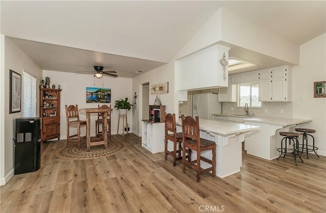 47384 Veater Ranch Rd, Coarsegold, CA 93614 - kitchen with a sink, a peninsula, a breakfast bar area, white fridge with ice dispenser, and light wood finished floors