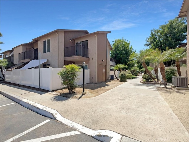 view of side of property featuring central AC, fence, and stucco siding