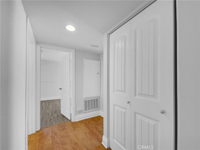 hall with visible vents, light wood-style flooring, and baseboards