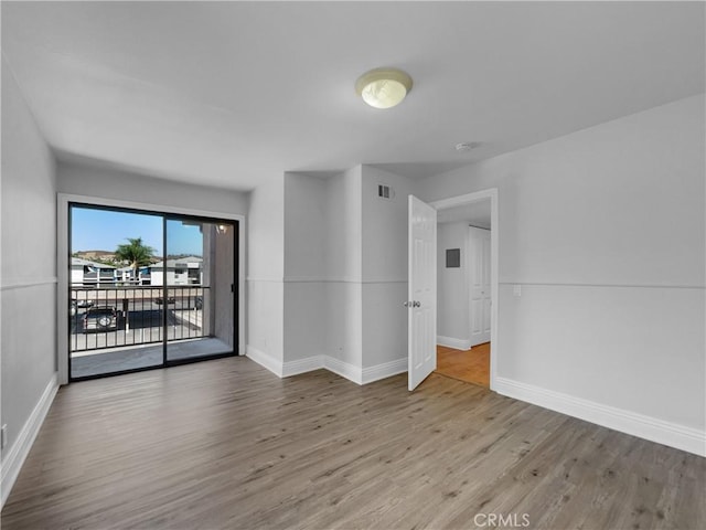 empty room featuring baseboards, visible vents, and wood finished floors