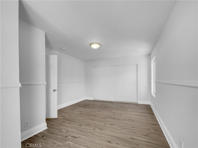 spare room featuring baseboards and wood finished floors