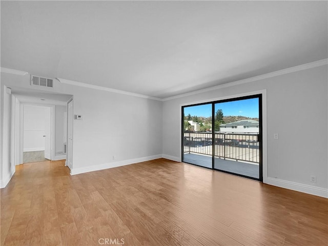 empty room with light wood-style flooring, crown molding, visible vents, and baseboards