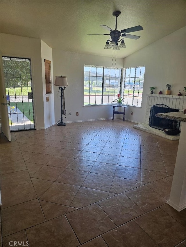 27865 Quincy St, Castaic, CA 91384 - unfurnished living room featuring plenty of natural light, a ceiling fan, a brick fireplace, dark tile patterned floors, and a textured ceiling