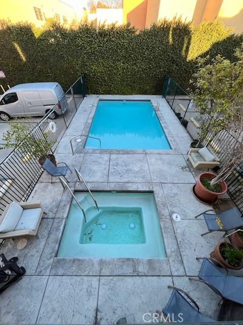 view of swimming pool featuring an in ground hot tub and fence