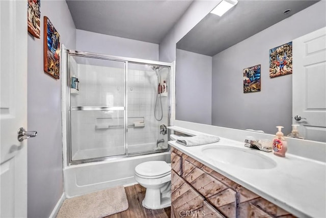 bathroom with toilet, enclosed tub / shower combo, wood finished floors, and vanity