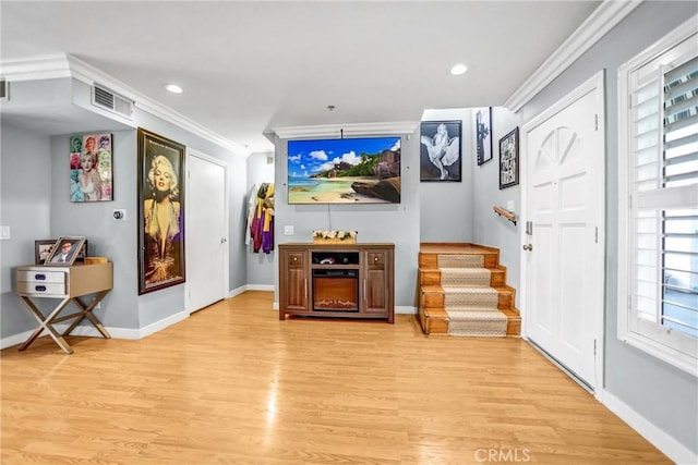 living area featuring baseboards, visible vents, stairs, crown molding, and light wood-type flooring