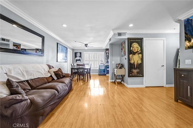 living room featuring light wood-style flooring, visible vents, baseboards, and ornamental molding