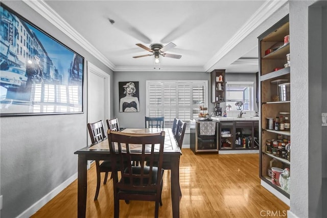 dining room featuring ornamental molding, baseboards, light wood finished floors, and a ceiling fan