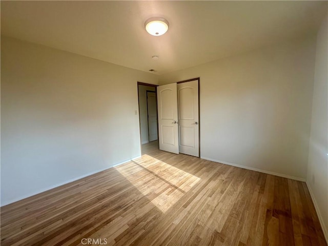 empty room with baseboards and light wood finished floors