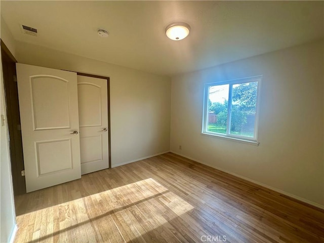 unfurnished bedroom featuring a closet, baseboards, visible vents, and wood finished floors