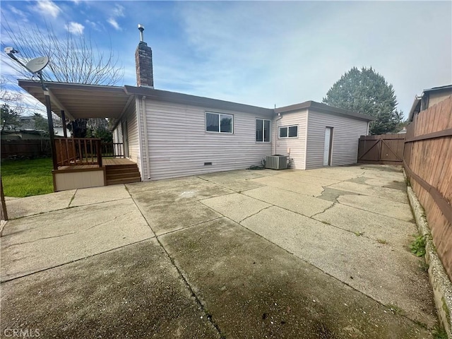 rear view of property featuring fence, central AC unit, a chimney, a deck, and a patio area