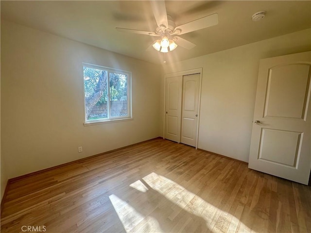 unfurnished bedroom featuring a closet, wood finished floors, and ceiling fan