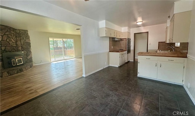kitchen with black electric cooktop, white cabinetry, a sink, open floor plan, and backsplash