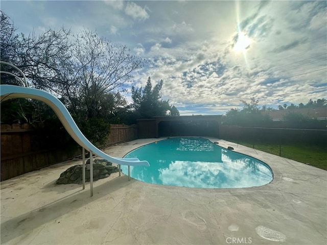 view of swimming pool featuring a fenced backyard, a water slide, a patio, and a fenced in pool