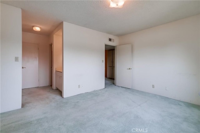 unfurnished bedroom with light carpet, a textured ceiling, and visible vents