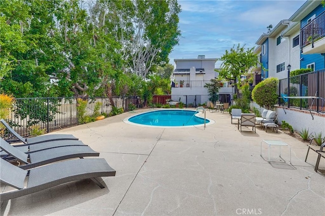 community pool with a patio area and fence