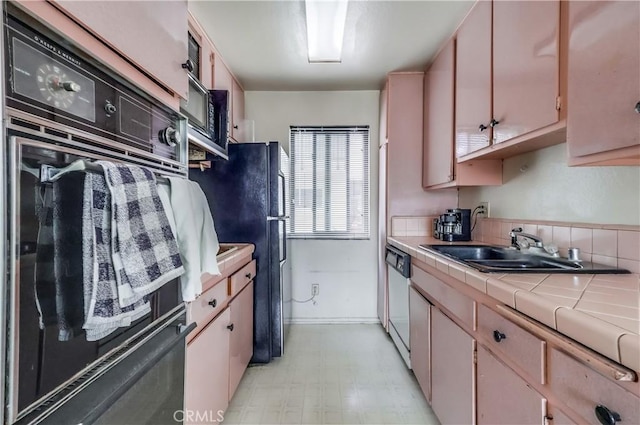 kitchen featuring light floors, black appliances, a sink, and tile counters