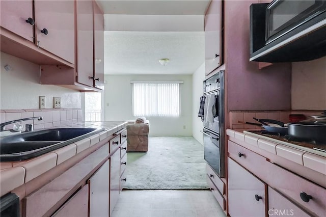 kitchen with light floors, tile counters, light colored carpet, white cabinetry, and a sink