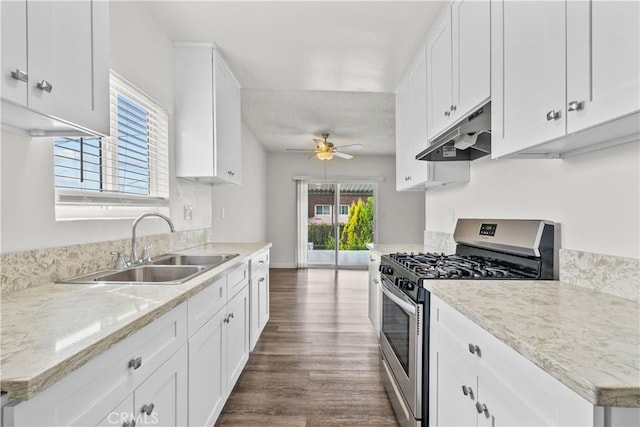 kitchen featuring under cabinet range hood, a sink, a ceiling fan, stainless steel gas range, and dark wood-style floors