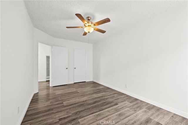 unfurnished bedroom with ceiling fan, a textured ceiling, baseboards, and wood finished floors