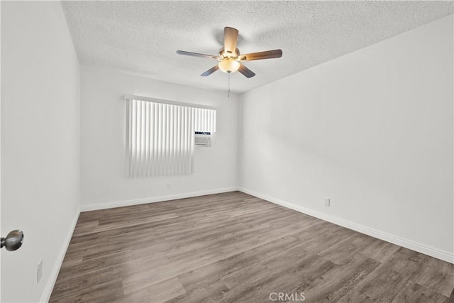 spare room featuring a ceiling fan, a textured ceiling, baseboards, and wood finished floors