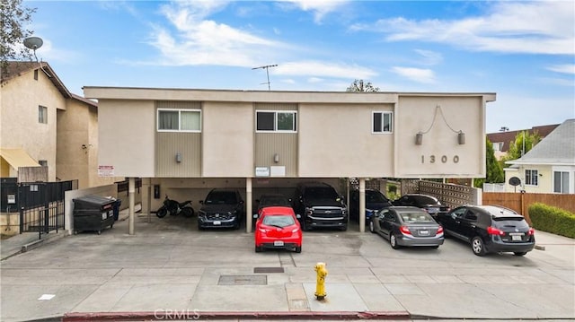 view of building exterior with covered parking and fence