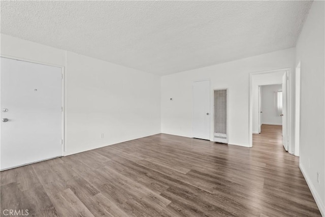 empty room with a textured ceiling and wood finished floors