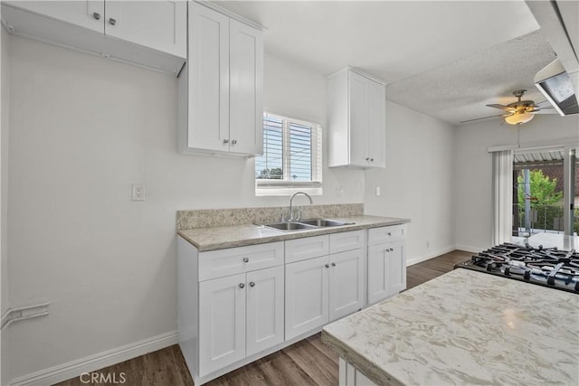 kitchen featuring white cabinetry, a sink, baseboards, and ceiling fan