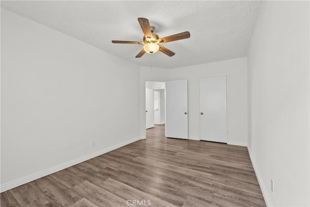 unfurnished bedroom featuring a ceiling fan, a textured ceiling, baseboards, and wood finished floors