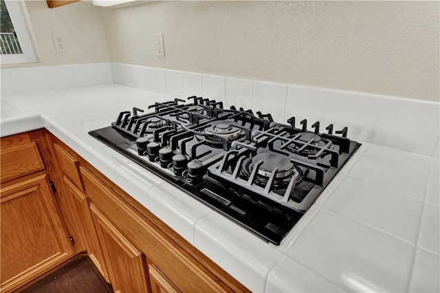 interior details featuring tile counters, brown cabinets, and black gas cooktop