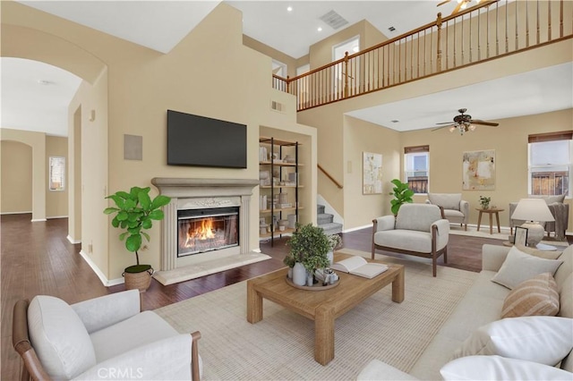 living area with plenty of natural light, visible vents, arched walkways, wood finished floors, and a fireplace