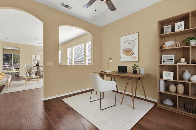 home office featuring dark wood-type flooring, a wealth of natural light, visible vents, and a ceiling fan