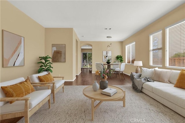 living room with arched walkways, wood finished floors, visible vents, and baseboards