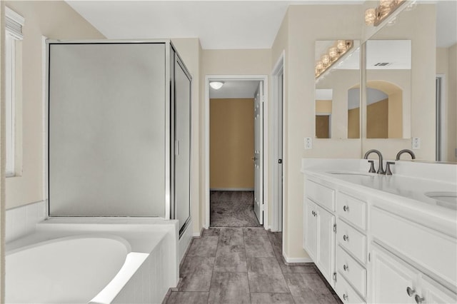 bathroom featuring a stall shower, a garden tub, a sink, and double vanity