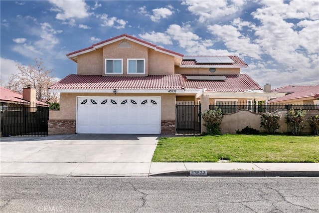 mediterranean / spanish home featuring solar panels, fence, concrete driveway, a front yard, and stucco siding